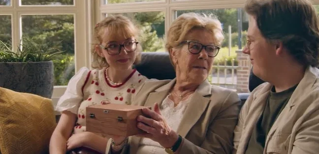 Drie generaties kijken samen naar de herinneringendoos op schoot