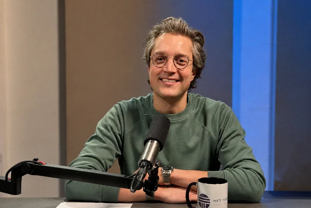 Man achter de microfoon aan de podcasttafel tijdens een opname